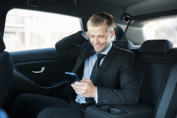 Young business client relaxing in back of black car